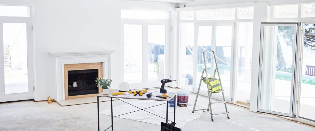 Shot of building plans and equipment on a table in an empty living room during the day.